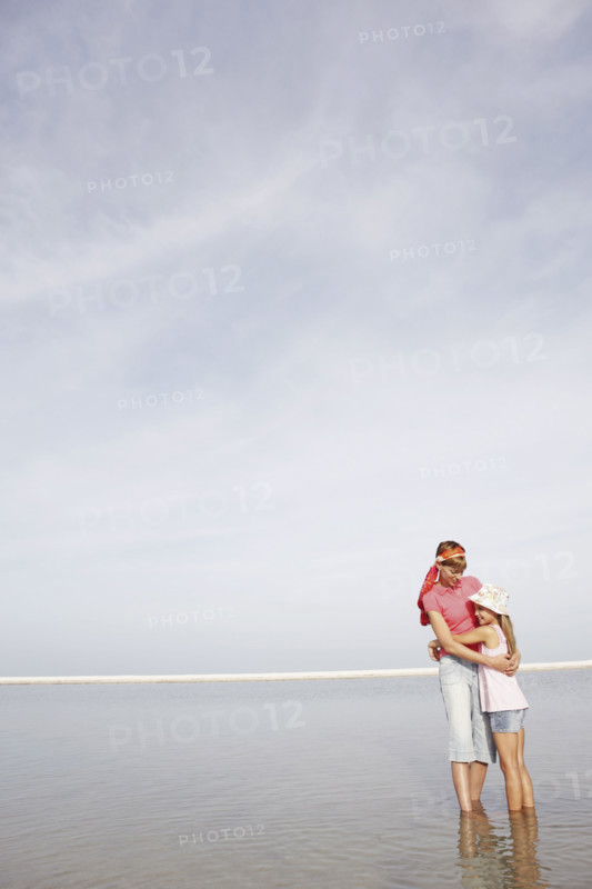 Mother and daughter hugging on beach. Date : 2008