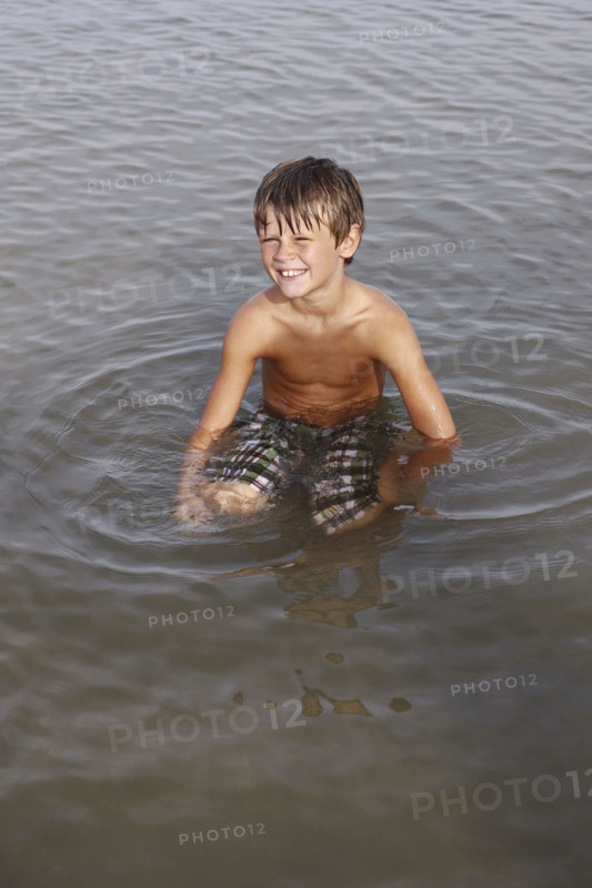 Boy sitting in shallow water. Date : 2008