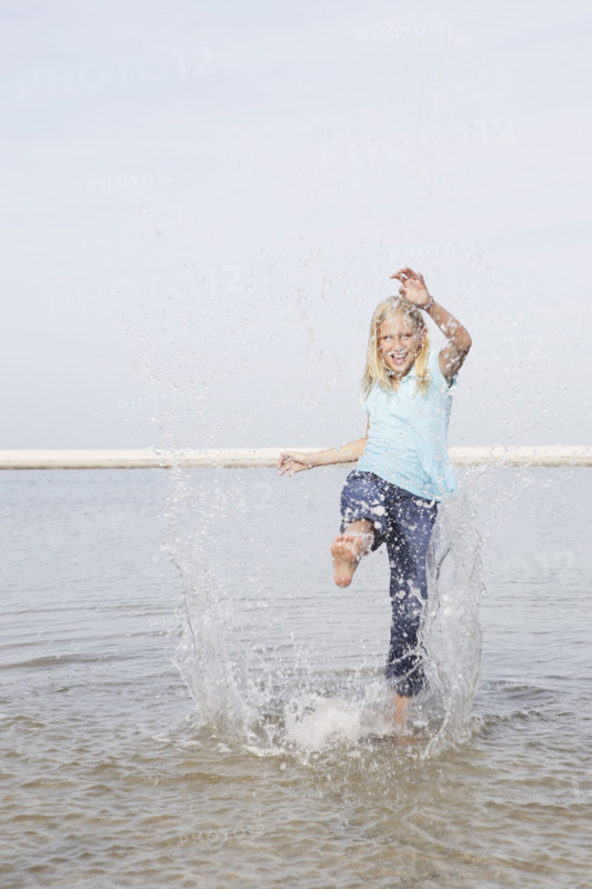 Girl kicking water at beach. Date : 2008
