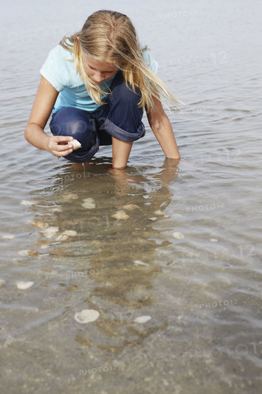 Girl looking for shells in shallow water. Date : 2008