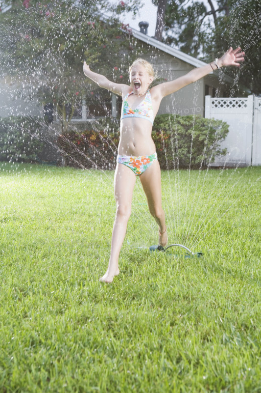Girl running through sprinklers. Date : 2008