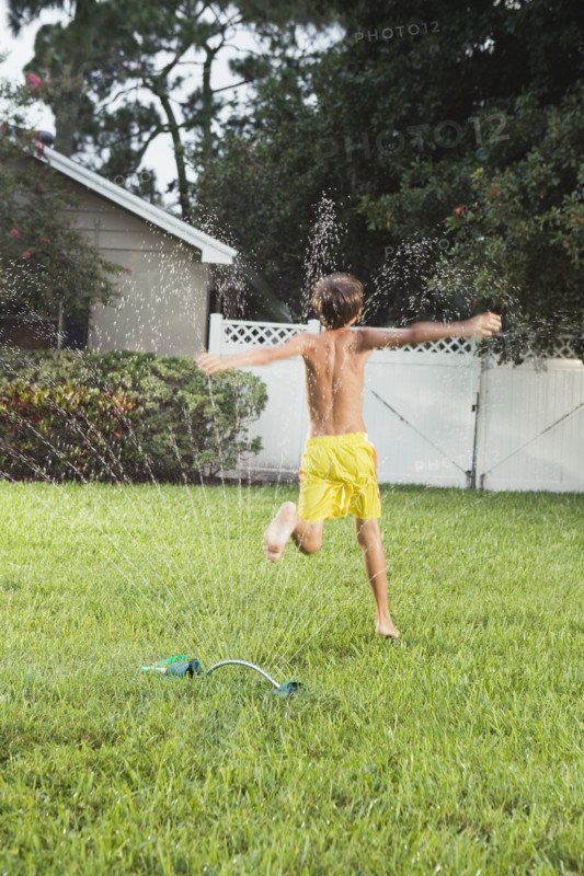 Boy running through sprinklers. Date : 2008