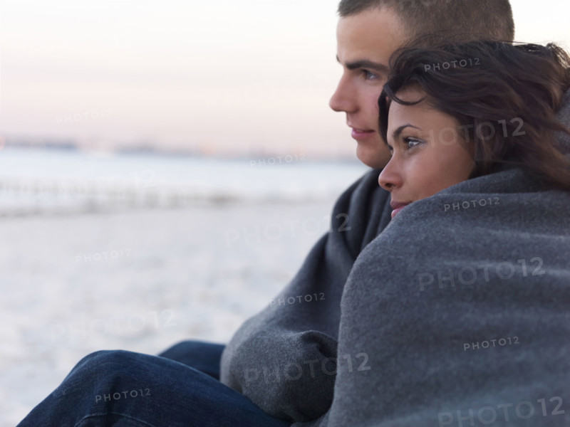 Young couple wrapped in blankets on beach. Date : 2008