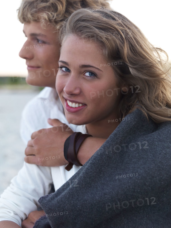 Young couple wrapped in blankets on beach. Date : 2008