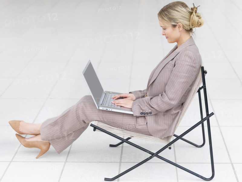 Businesswoman working on laptop in modern chair. Date : 2008
