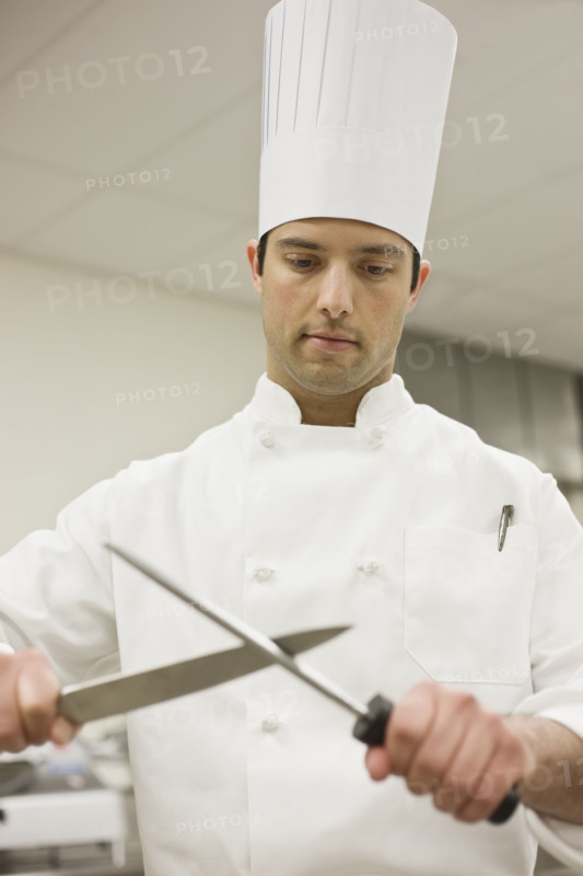 Chef sharpening knife in kitchen. Date : 2008