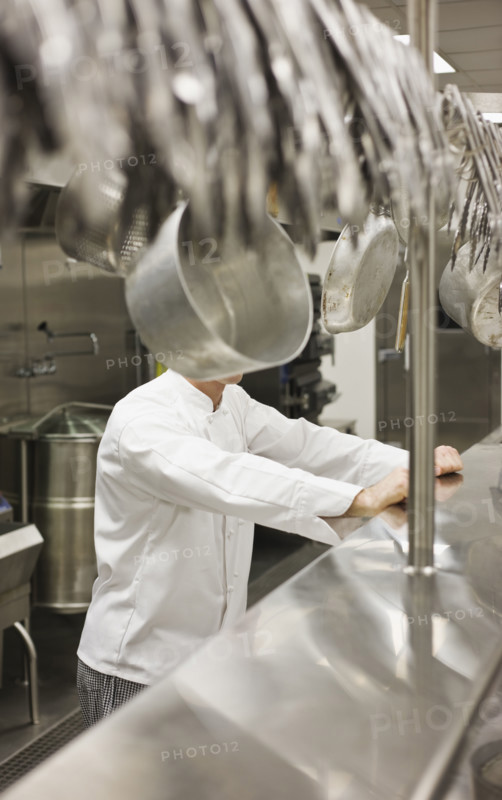 Chef leaning on shelf in commercial kitchen. Date : 2008