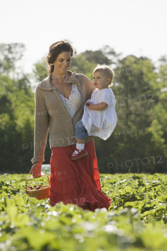 Mother and baby daughter picking strawberries. Date : 2008