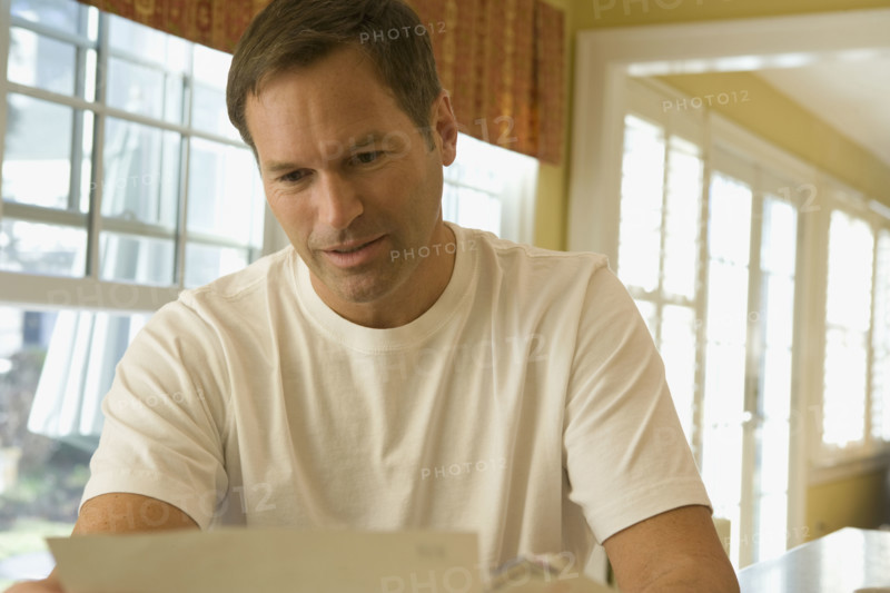 Man reading letter at home. Date : 2008