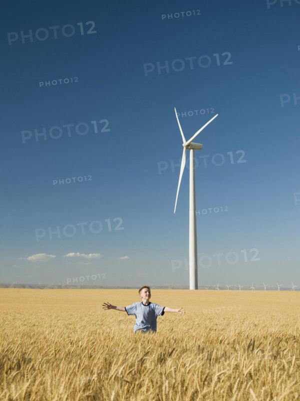 Boy running through field on wind farm. Date : 2008