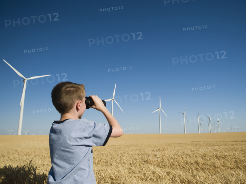 Boy on wind farm looking through binoculars. Date : 2008