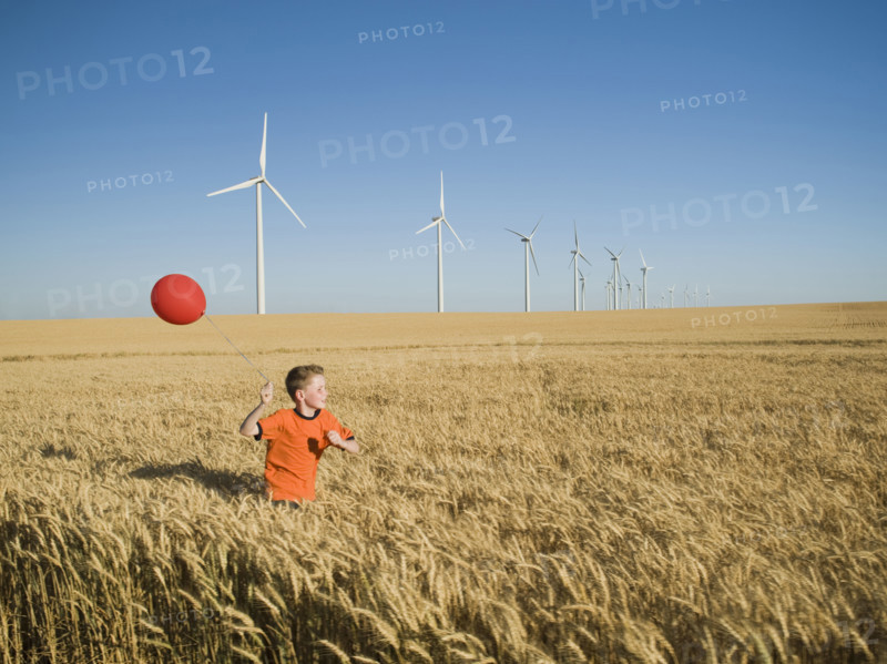 Boy running with balloon on wind farm. Date : 2008