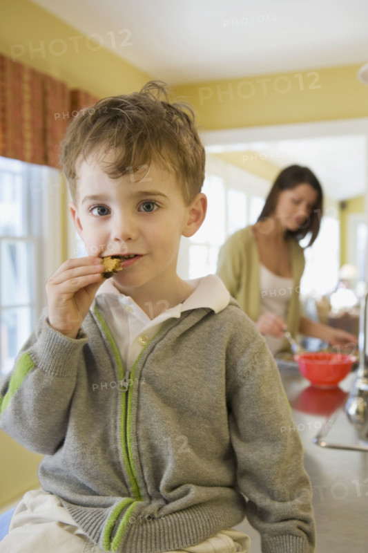 Boy eating cookie on kitchen counter. Date : 2008