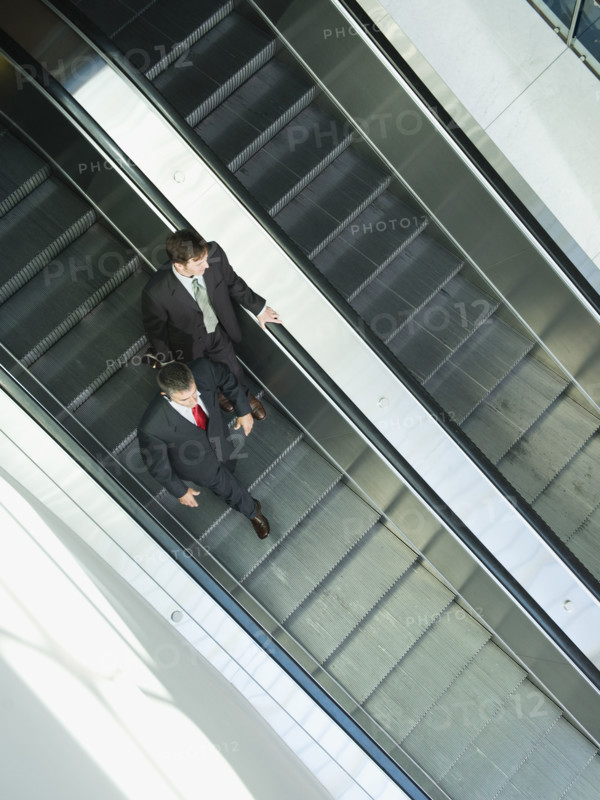 Businessmen descending escalator. Date : 2008