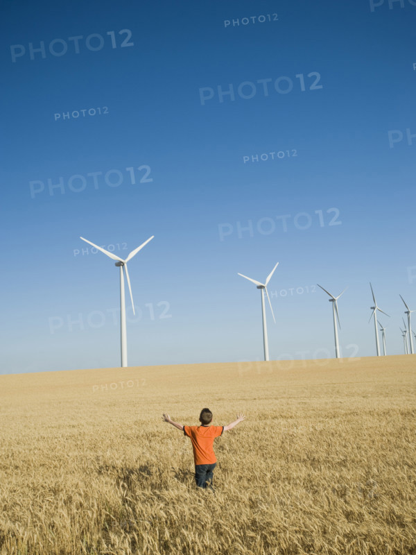 Boy standing in field on wind farm. Date : 2008
