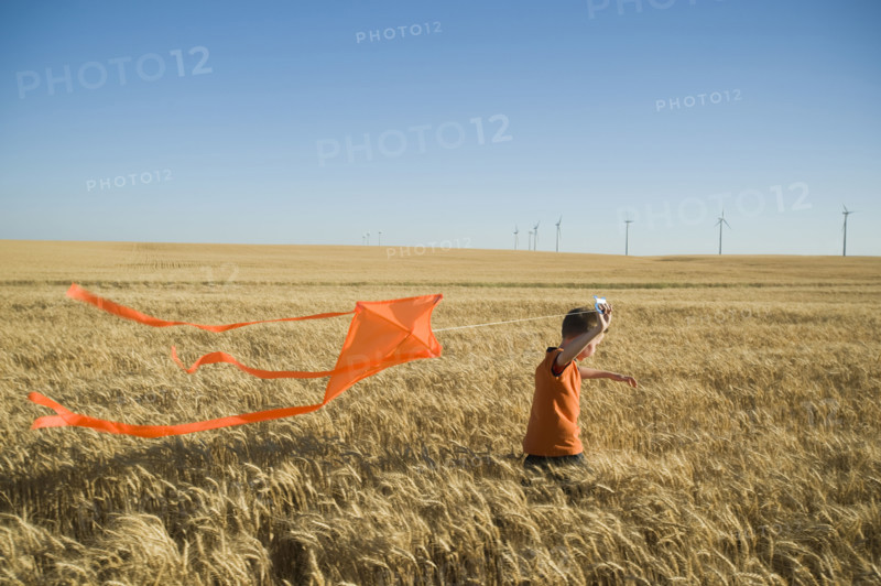 Boy running with kite on wind farm. Date : 2008