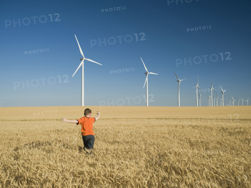 Boy running through field on wind farm. Date : 2008