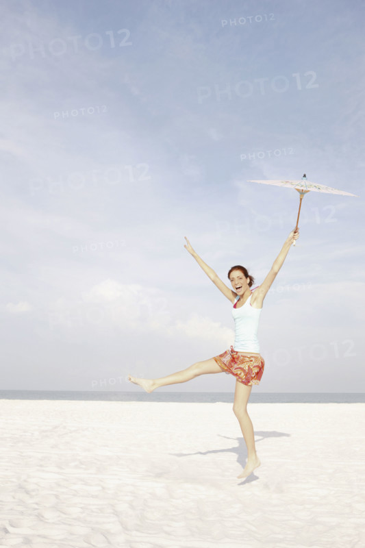 Girl holding umbrella and dancing on beach. Date : 2008