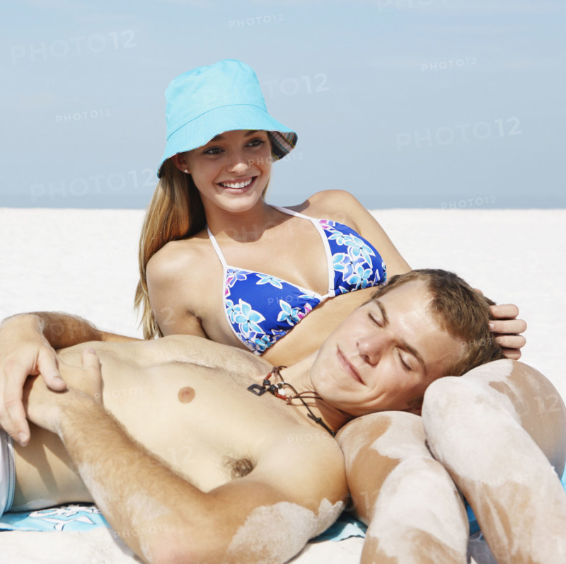 Young couple leisurely sunbathing on beach. Date : 2008
