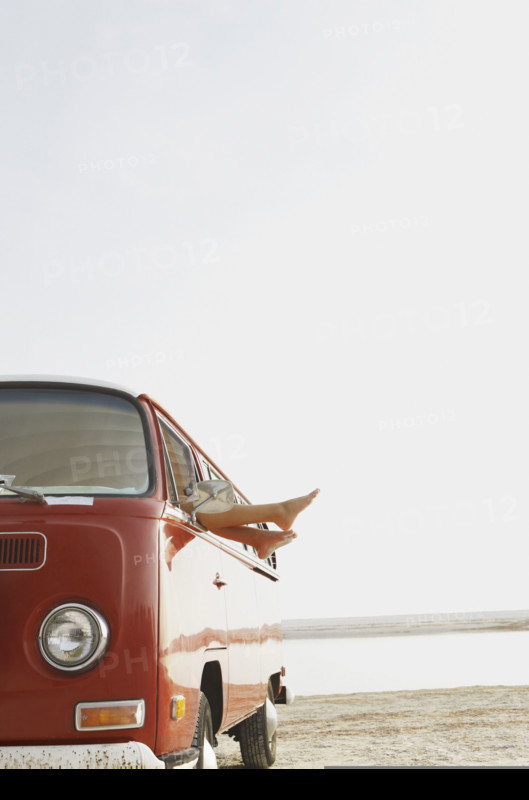 Feet sticking out of van window on beach. Date : 2008