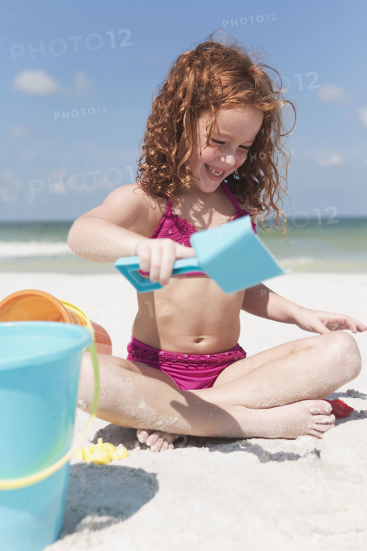 Girl digging in sand on beach. Date : 2008