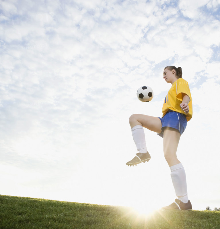 Teenage girl bouncing soccer ball on knee. Date: 2008