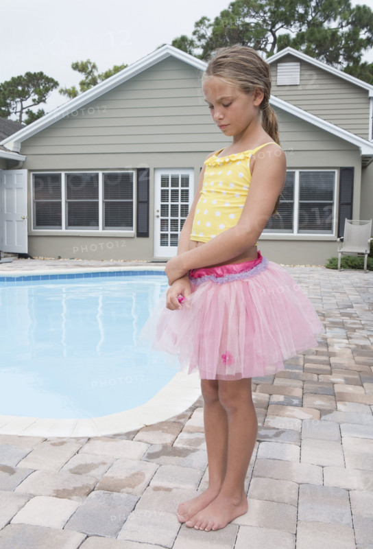 Girl standing at poolside looking sad. Date: 2008
