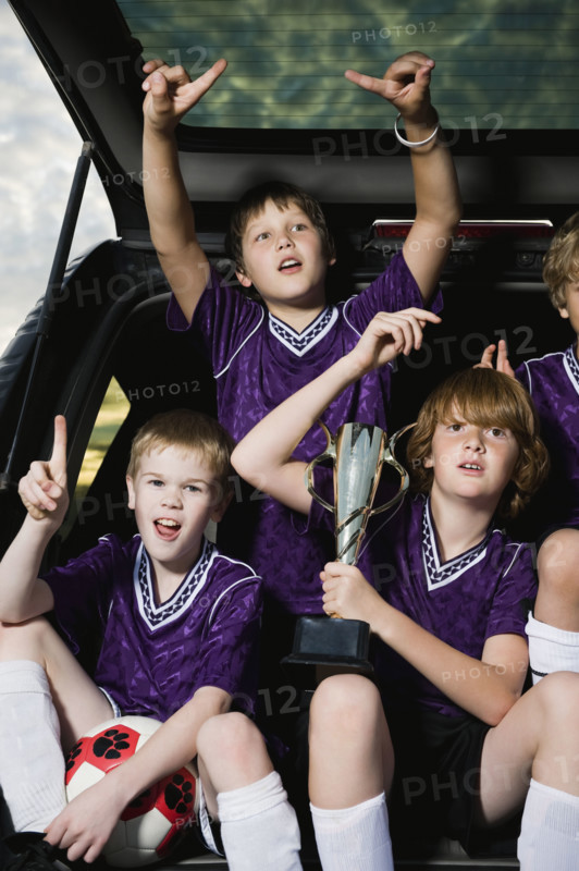 Boys soccer team holding trophy in back of car. Date : 2008