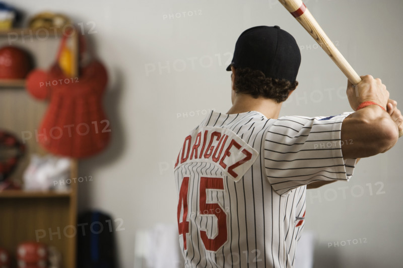 Baseball player practicing swing in locker room. Date: 2008