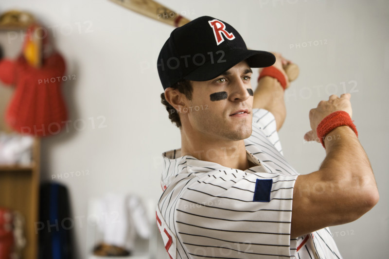 Baseball player practicing swing in locker room. Date: 2008