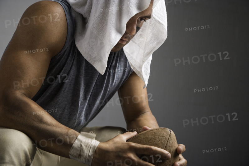 Football player with towel on head holding football. Date: 2008