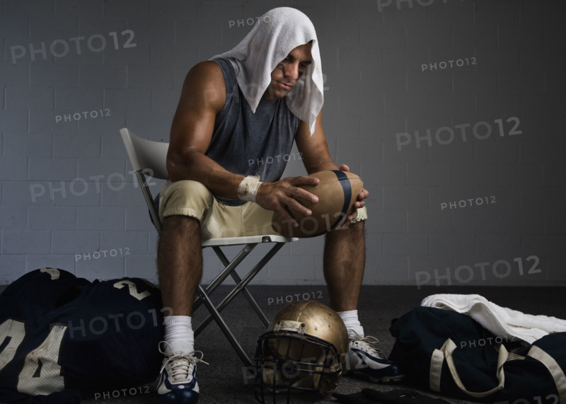Football player with towel on head in locker room. Date: 2008