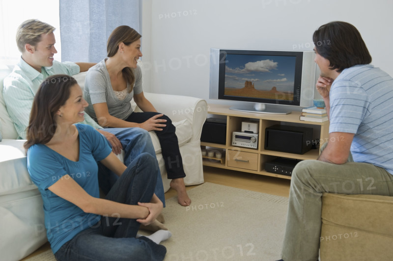 Couples watching television in living room.