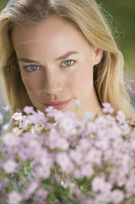 Woman posing behind flowers.