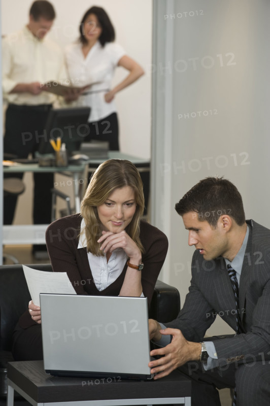 Businessman and businesswoman using laptop.