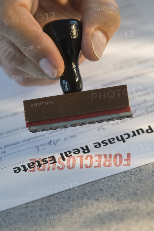 Man stamping “foreclosure” on mortgage form.