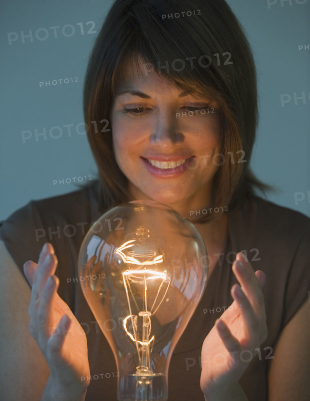 Woman holding hands around large light bulb.
