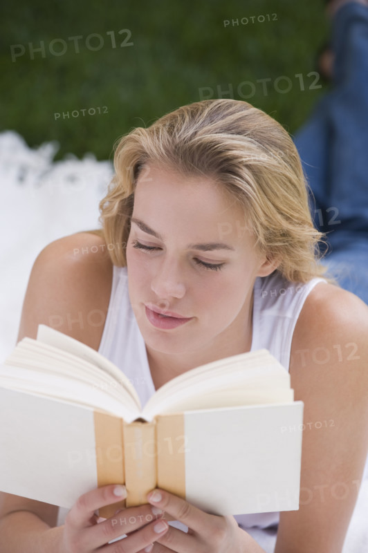 Woman reading book outdoors.