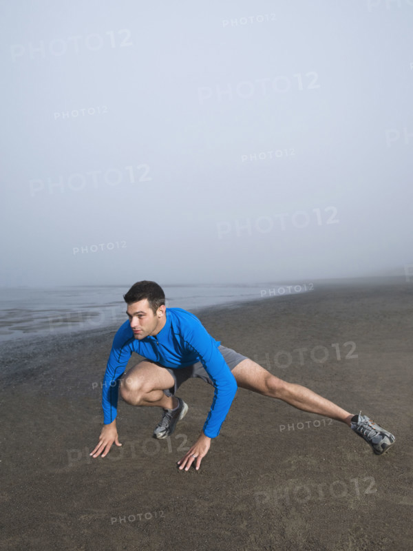 Man stretching on foggy beach. Date : 2008