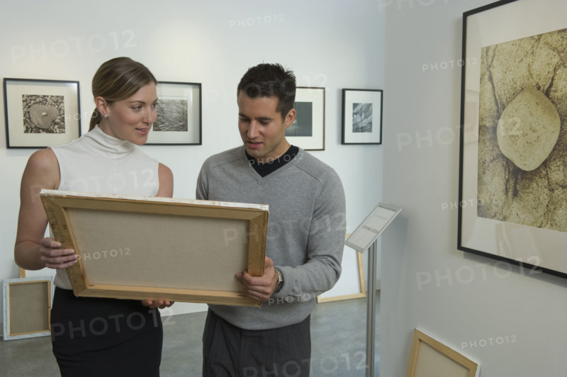 Curators examining painting in art gallery.