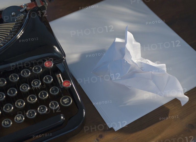 Crumpled paper next to antique typewriter.