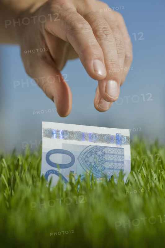 Close up of hand reaching for twenty euro bill.