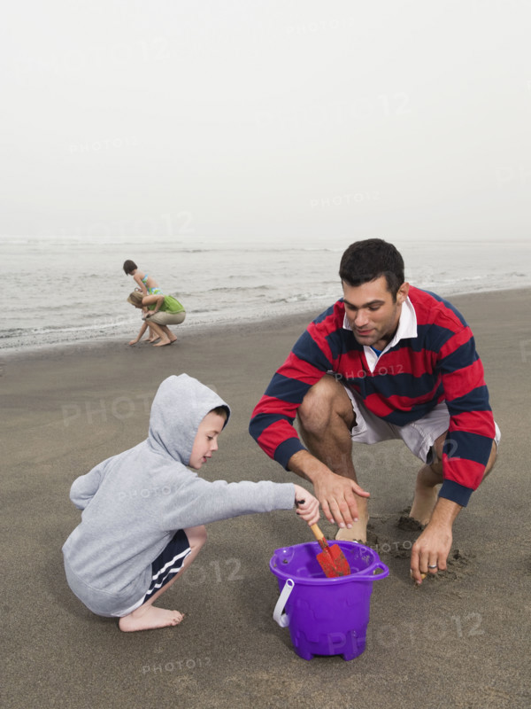 Family looking for shells on beach. Date: 2008