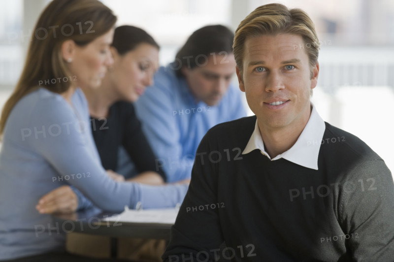 Portrait of businessman with business people in background.