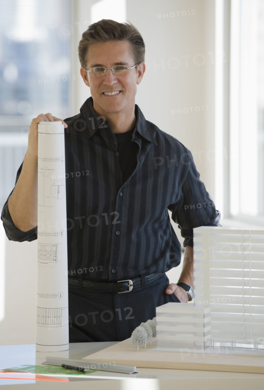 Portrait of architect with blueprint and building model.