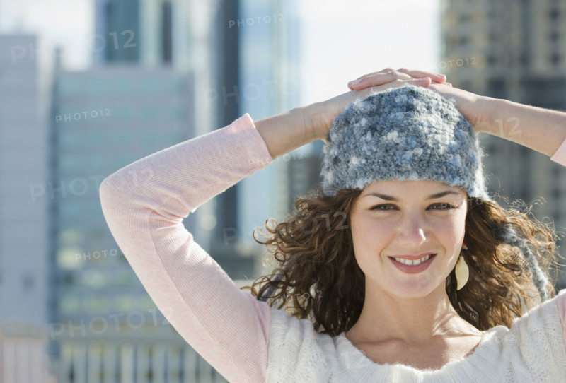 Portrait of woman in stocking cap with city in background.