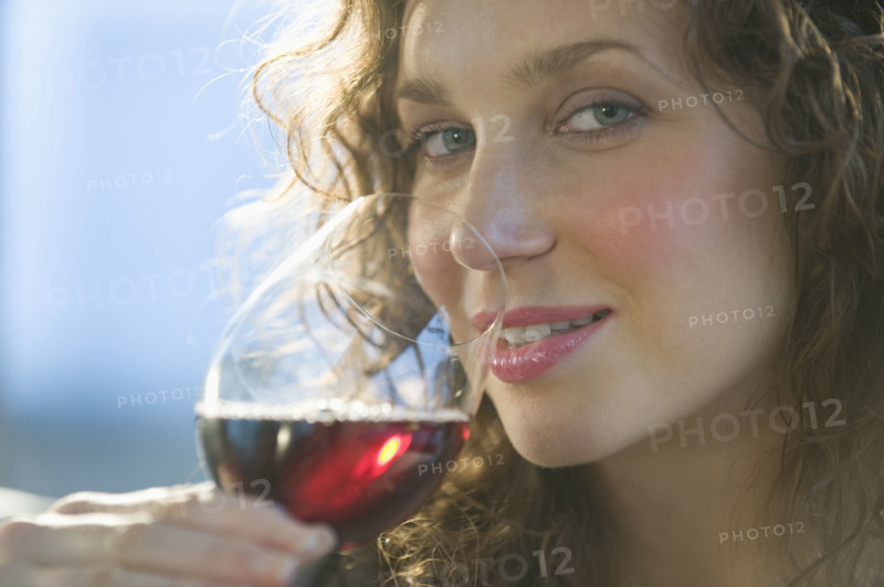 Close up portrait of woman smelling red wine.
