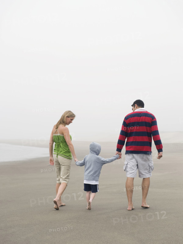 Parents holding hands with son on beach. Date: 2008