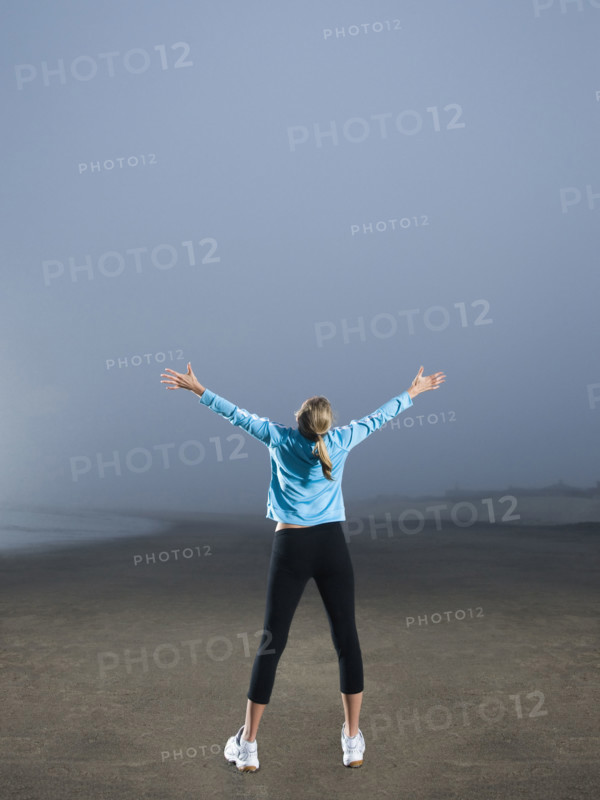 Woman with arms outstretched on foggy beach. Date : 2008
