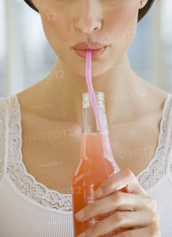 Close up of woman drinking soda from a straw.